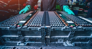 person wearing green gloves handling an electric vehicle battery rig