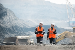 image of two workers in orange vests and hard hats at a mining site