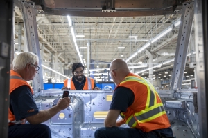 image of three workers in reflective vests working at an automotive parts factory