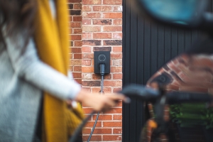 photograph of woman charging her money-saving electric vehicle at home