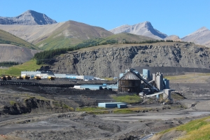 photograph of a mining site against mountains and blue sky