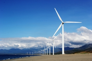 image of wind farm in front of mountains and white-clouded blue sky