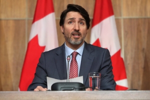 Canada's prime minister justin trudeau seated and speaking behind a microphone