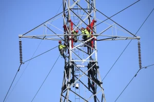 photograph of technicians working on maintenance on a power transmission tower